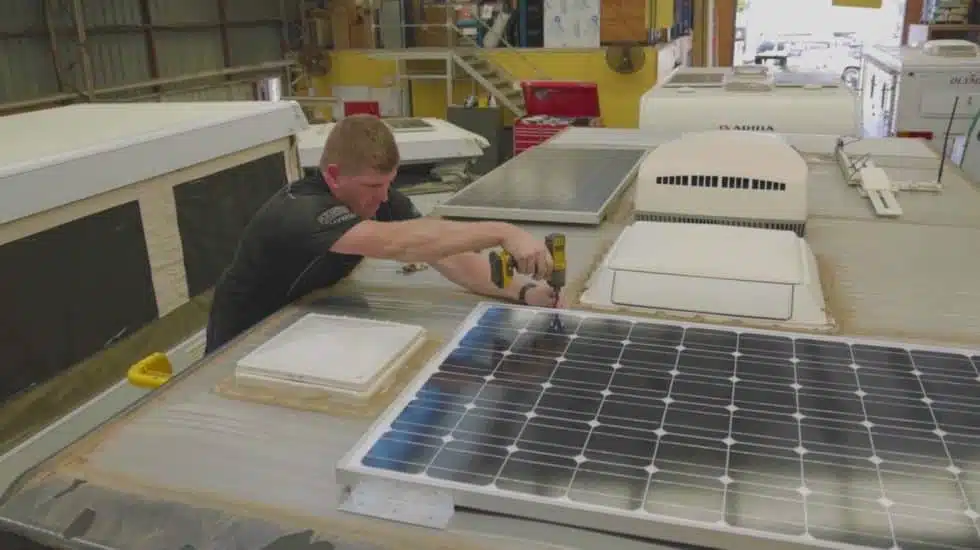 man installing solar panel on the van roof