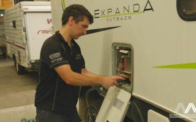 man flushing out hot water system in caravan