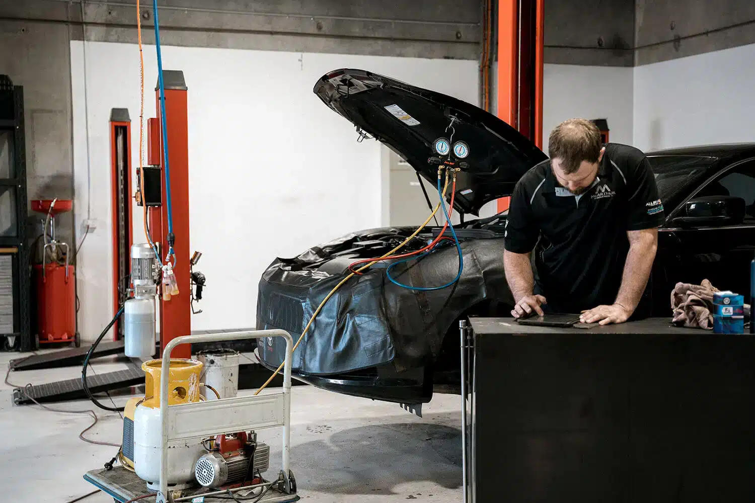 Red car with open hood parked in a repair shop for maintenance