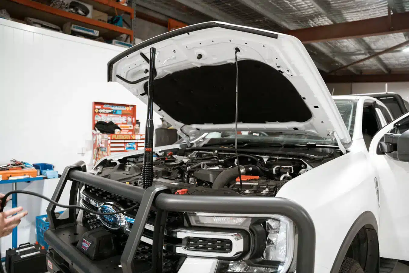 Car undergoing mechanical inspection with hood open in a repair bay