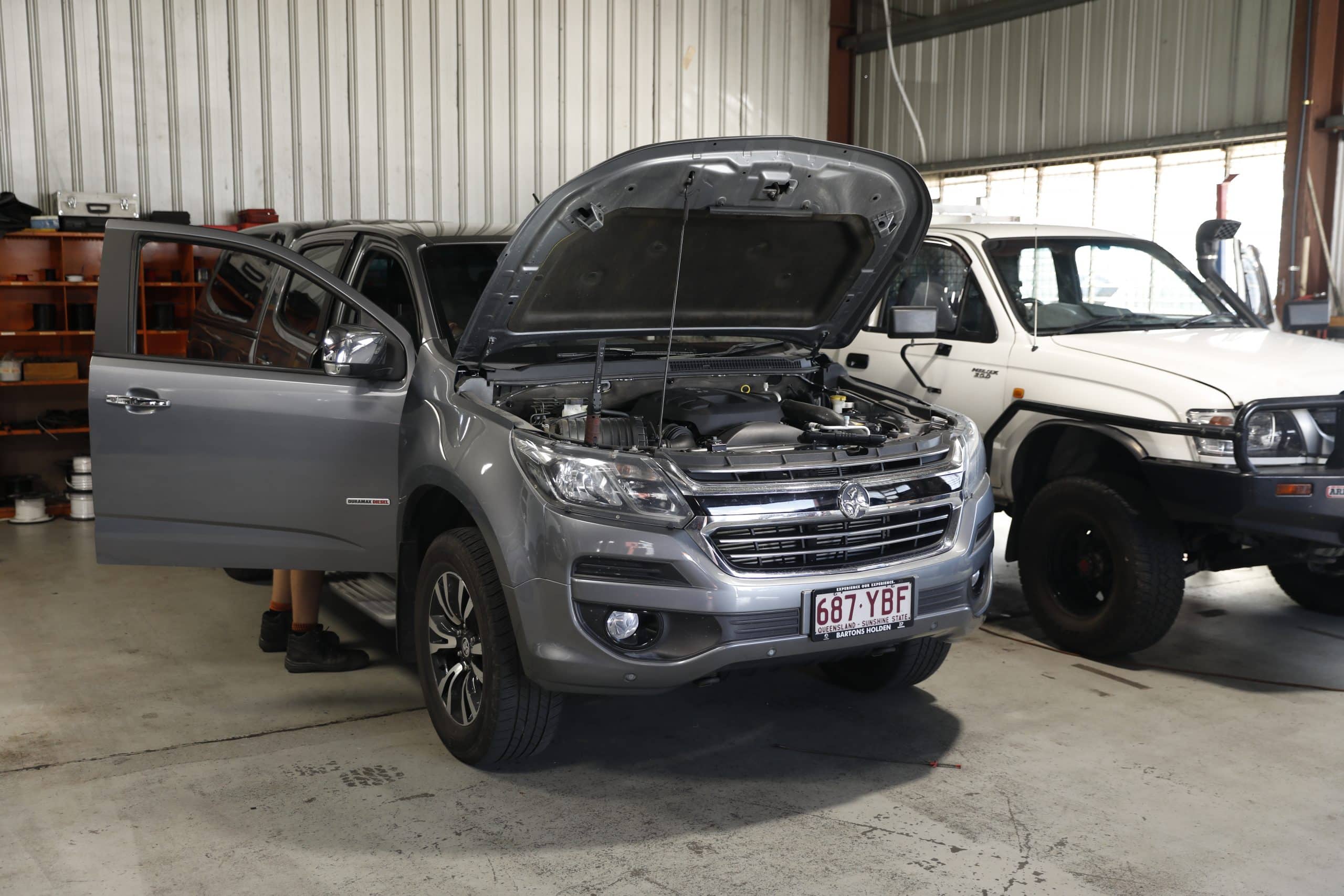 Car undergoing repairs with hood open in a workshop