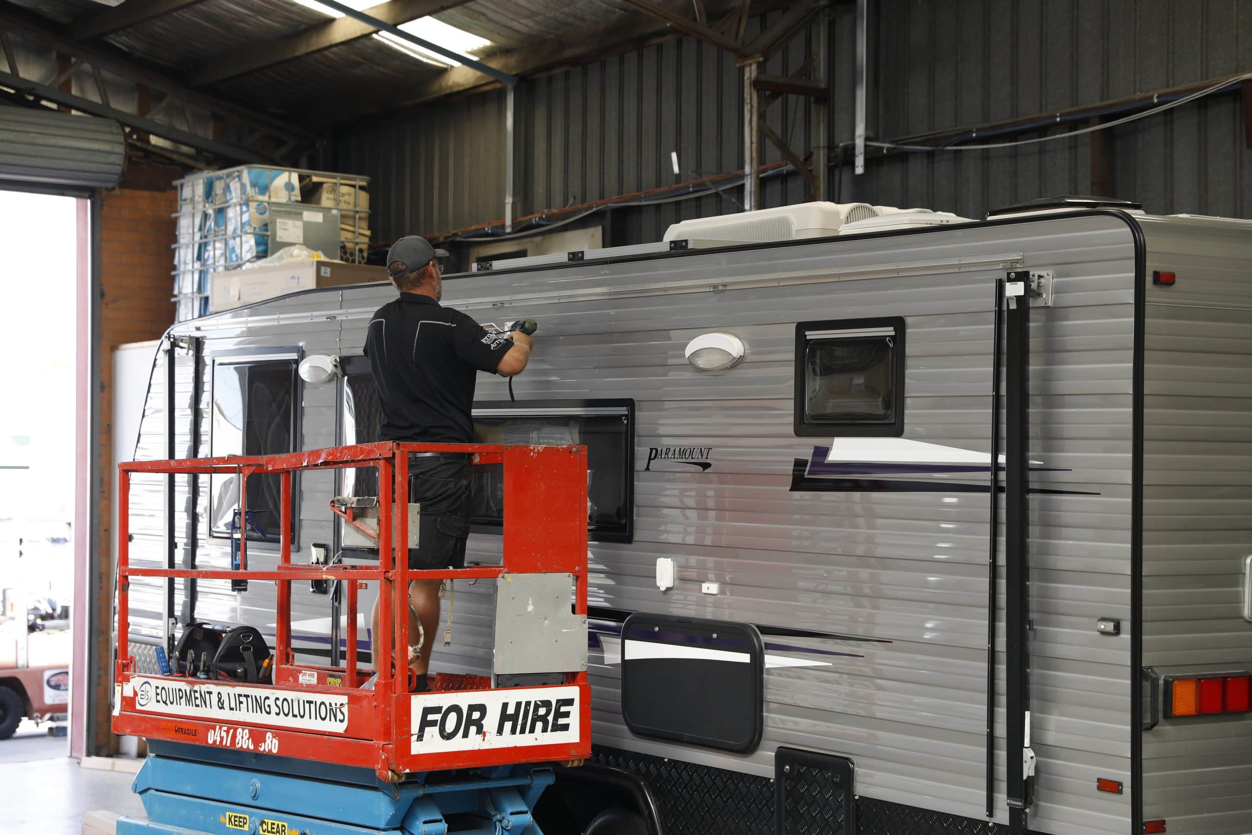 Technician servicing a caravan parked inside a workshop